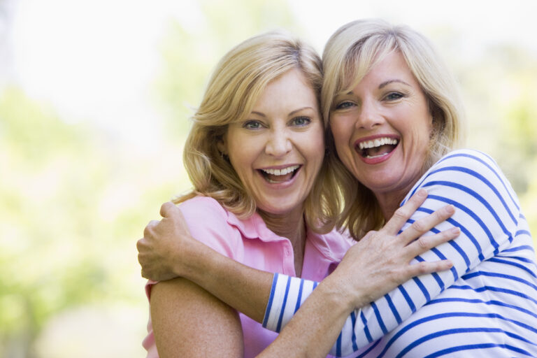 Two,Women,Outdoors,Hugging,And,Smiling